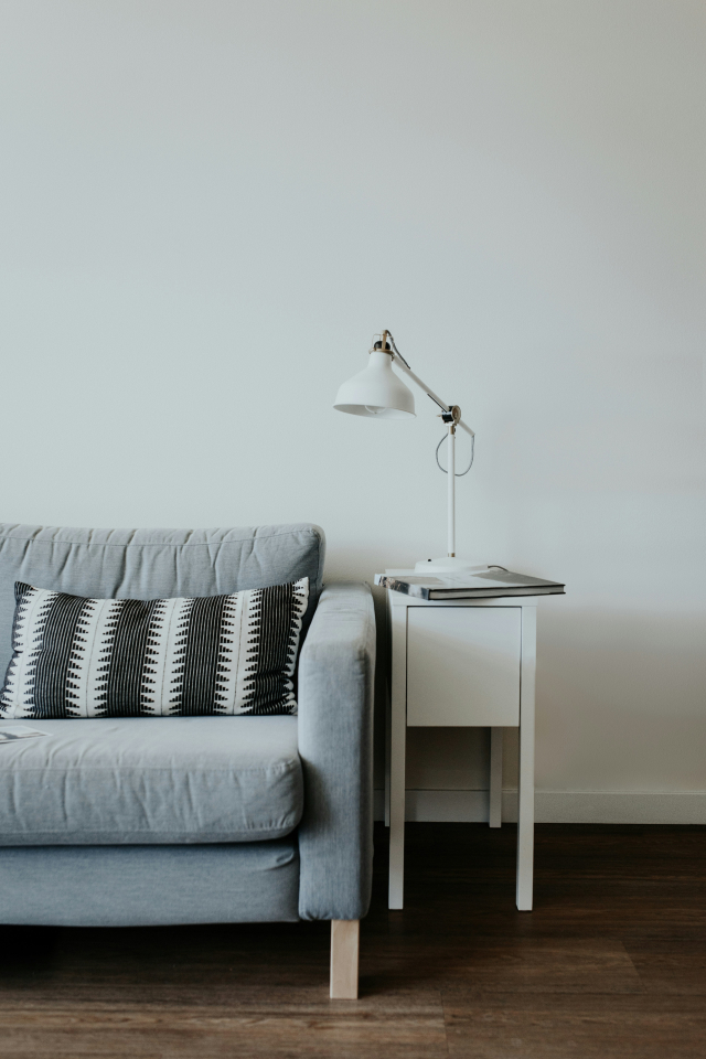 Ein graues Sofa mit Beistelltisch und Leselampe. Von Becca Tapert auf Unsplash.